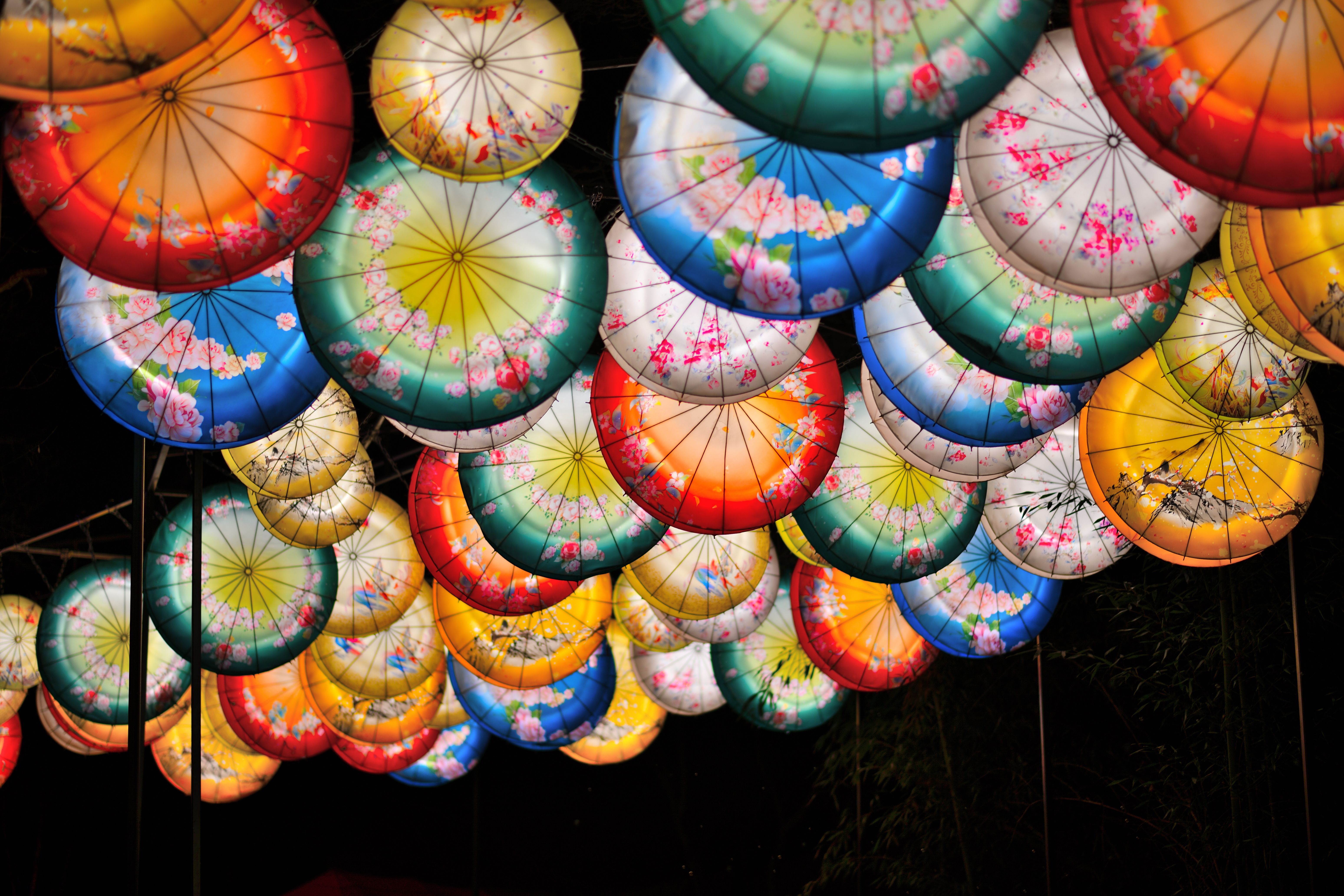 Free Colorful umbrella lanterns create a vivid display at a night festival, capturing vibrant cultural aesthetics. Stock Photo