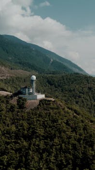 A weather station overlooking lush forests in the Turkish mountains offers a stunning landscape view.