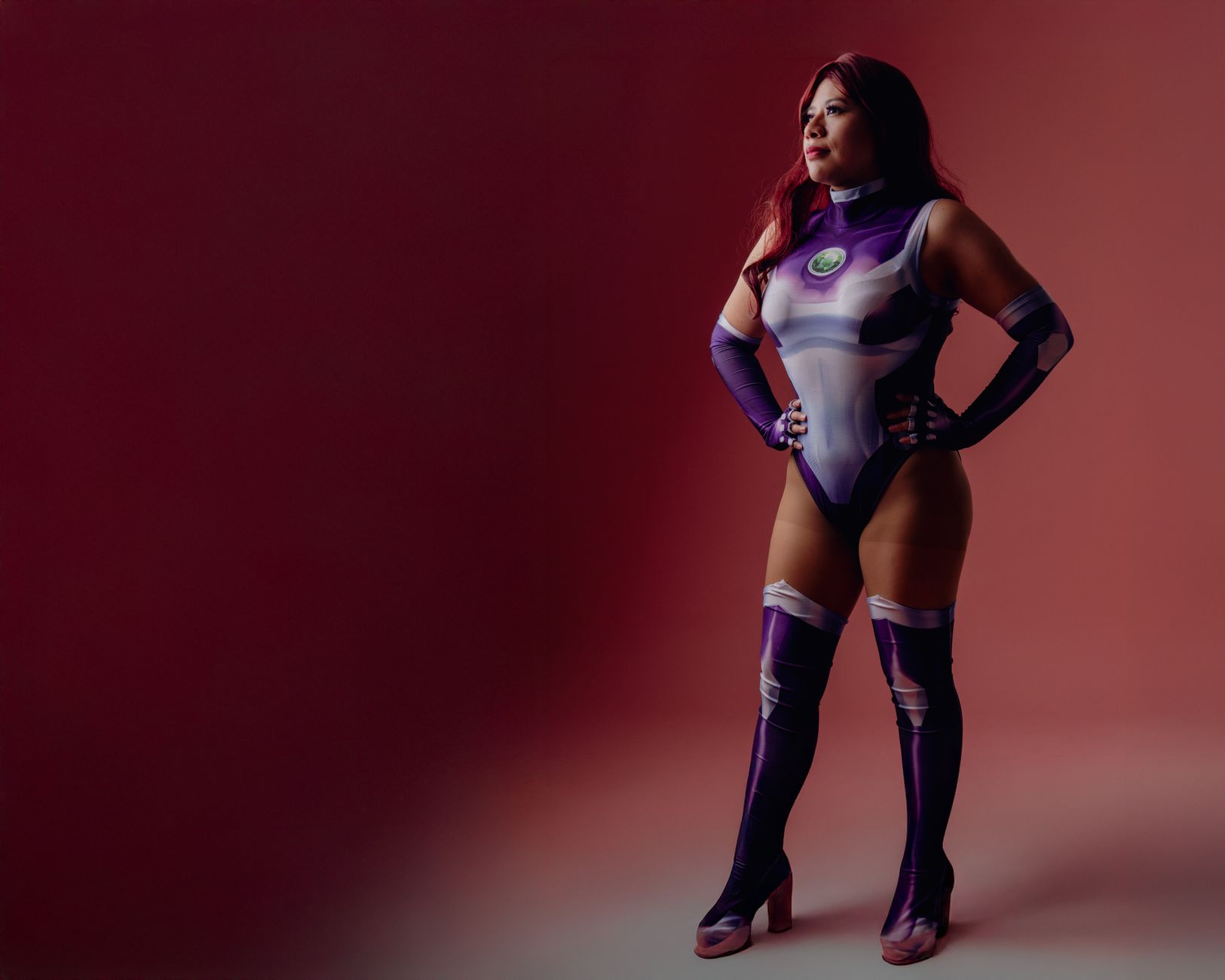 Colorful cosplay of a woman in superhero attire against a pink backdrop.
