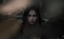 神秘的女人脸上画着符号，周围都是树叶