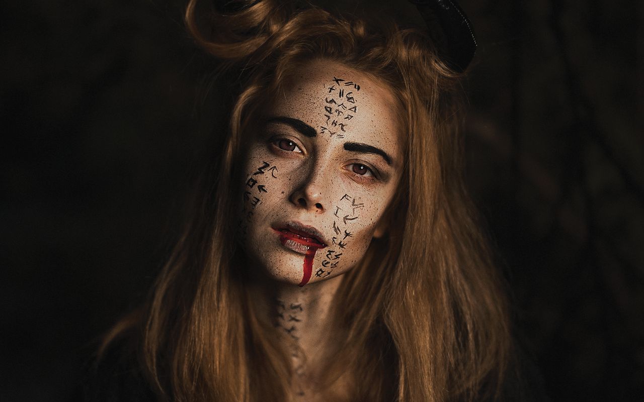 eerie portrait of a woman with intricate face paint and dark makeup pe