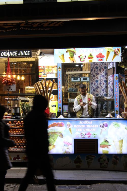 Free A street vendor in traditional attire selling ice cream at night in a bustling market. Stock Photo