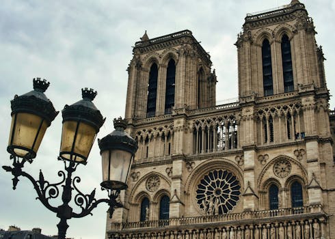 Close-up photo of Notre Dame Cathedral's iconic facade in Paris, showcasing gothic architecture and a streetlamp.