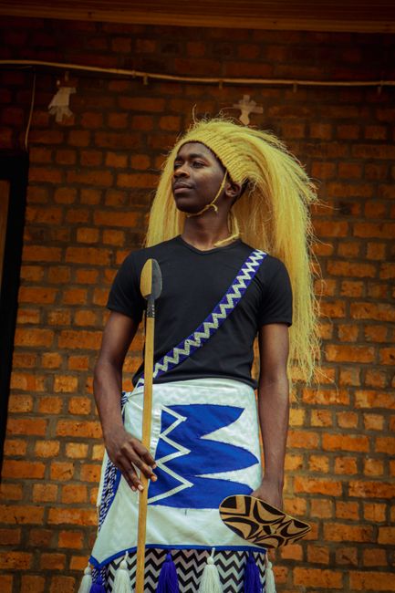 Young man in traditional attire with spear and shield, vibrant cultural expression.