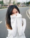 在一个阳光明媚的日子里，一位面带微笑的女人穿着超大号白色毛衣，俏皮地摆着姿势