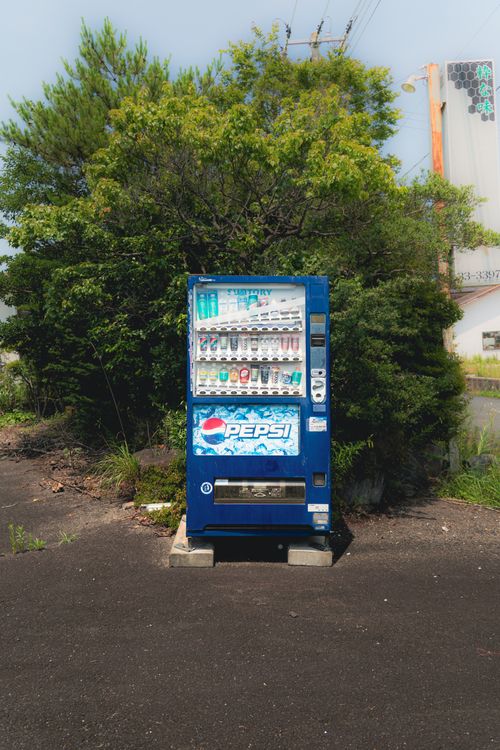 Free A solitary Pepsi vending machine stands outdoors against a green backdrop, offering a variety of drinks. Stock Photo