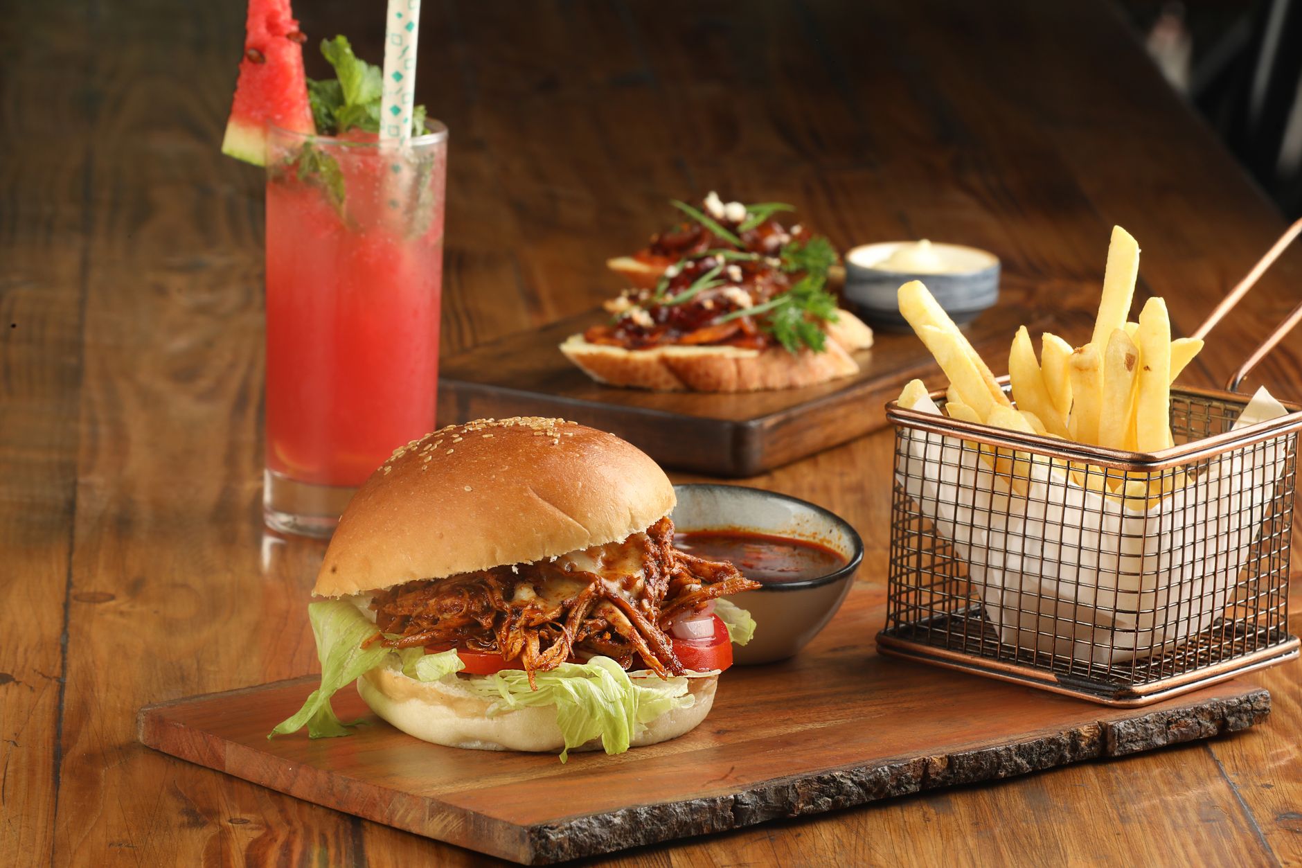 A burger with lettuce, tomato, and onion on a wooden plate