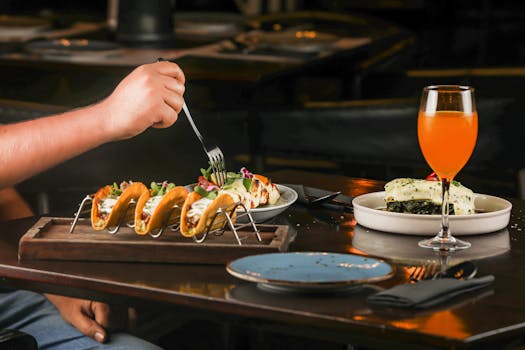 A flavorful dining setup featuring tacos, a refreshing beverage, and a gourmet plated dish indoors.