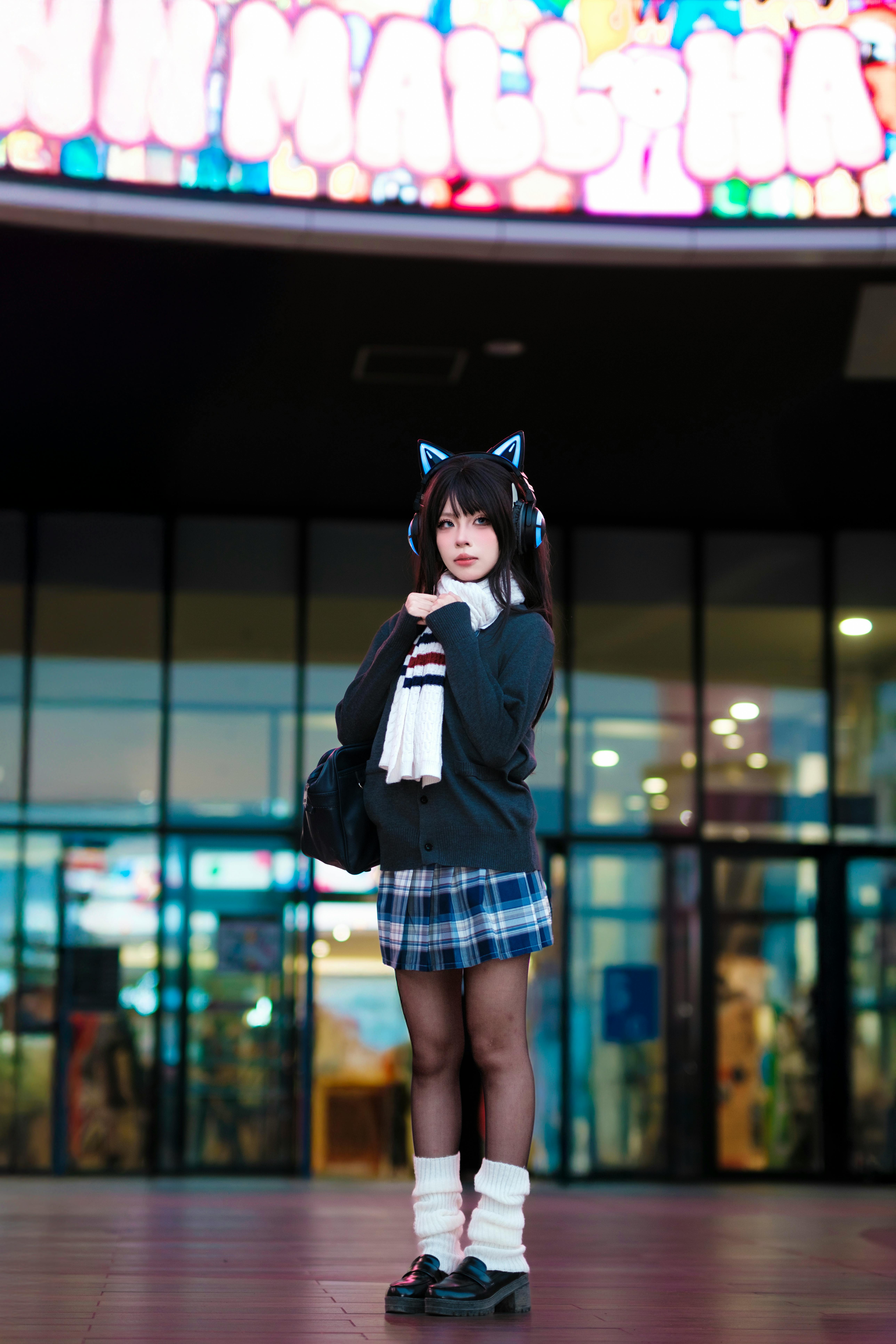 Young girl in cosplay attire outside a mall with colorful neon signs.