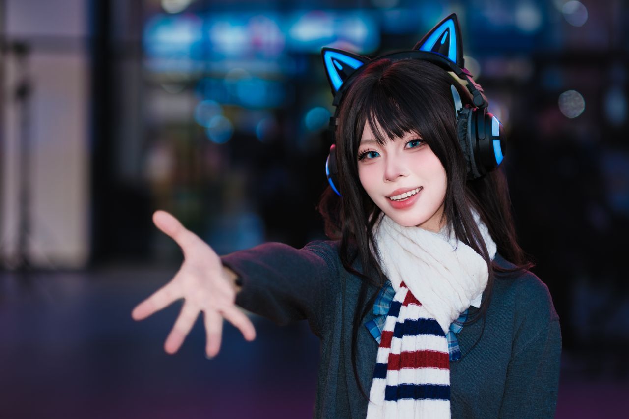 young woman smiling and wearing cat ear headphones reaching out with a