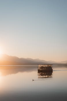 Tranquil scene of a boat on a calm lake during a serene sunset.