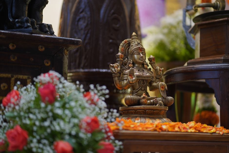 Intricately designed Hindu deity statue with bright floral arrangements indoors.