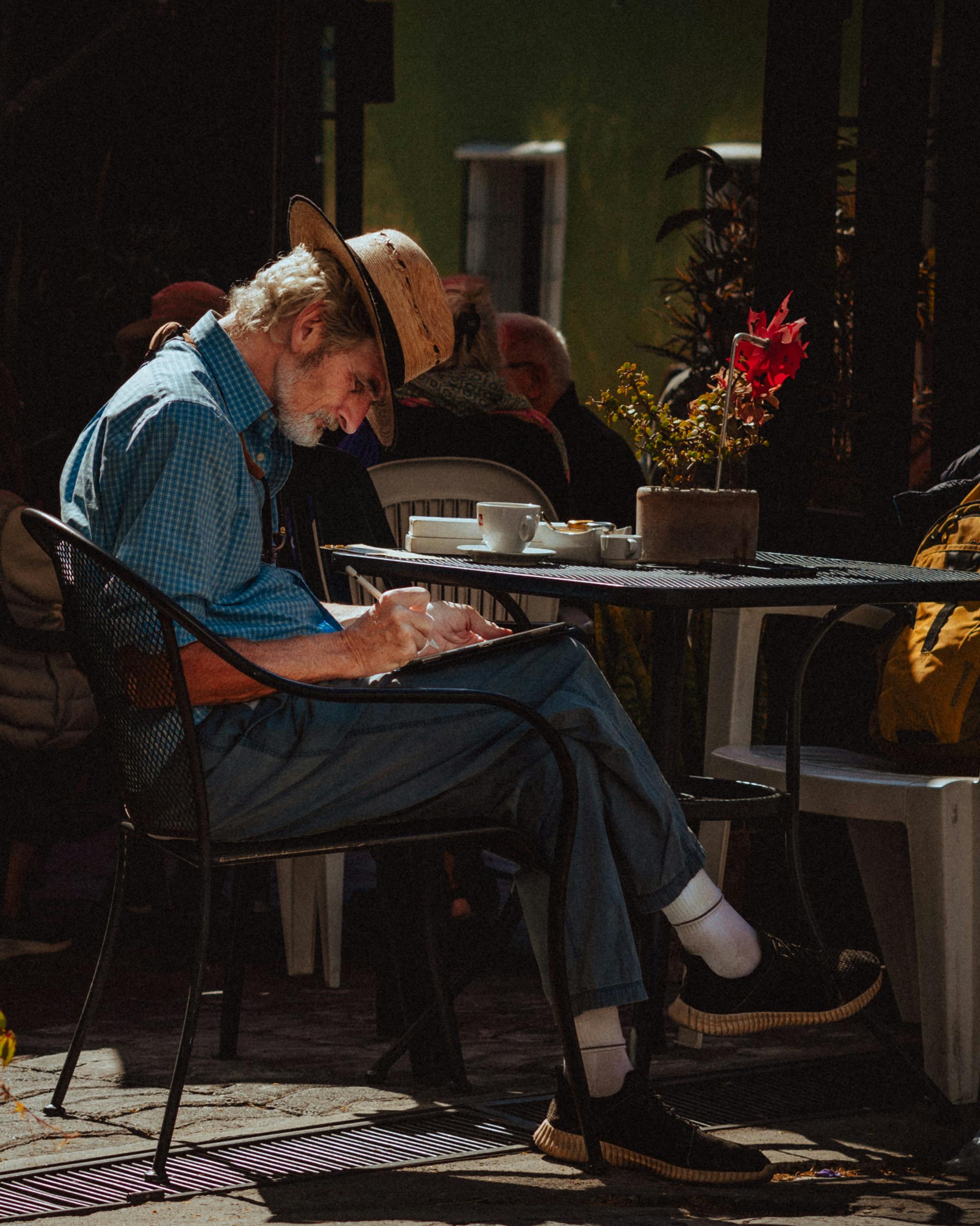 Elderly man enjoying a peaceful moment with a book at a cozy outdoor café in Puebla, Mexico.
