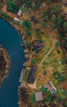 Aerial photo showcasing rural houses by a winding river surrounded by trees in autumn.