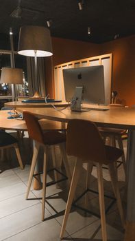 A stylish office setup with warm lighting, featuring modern furniture and computer equipment.