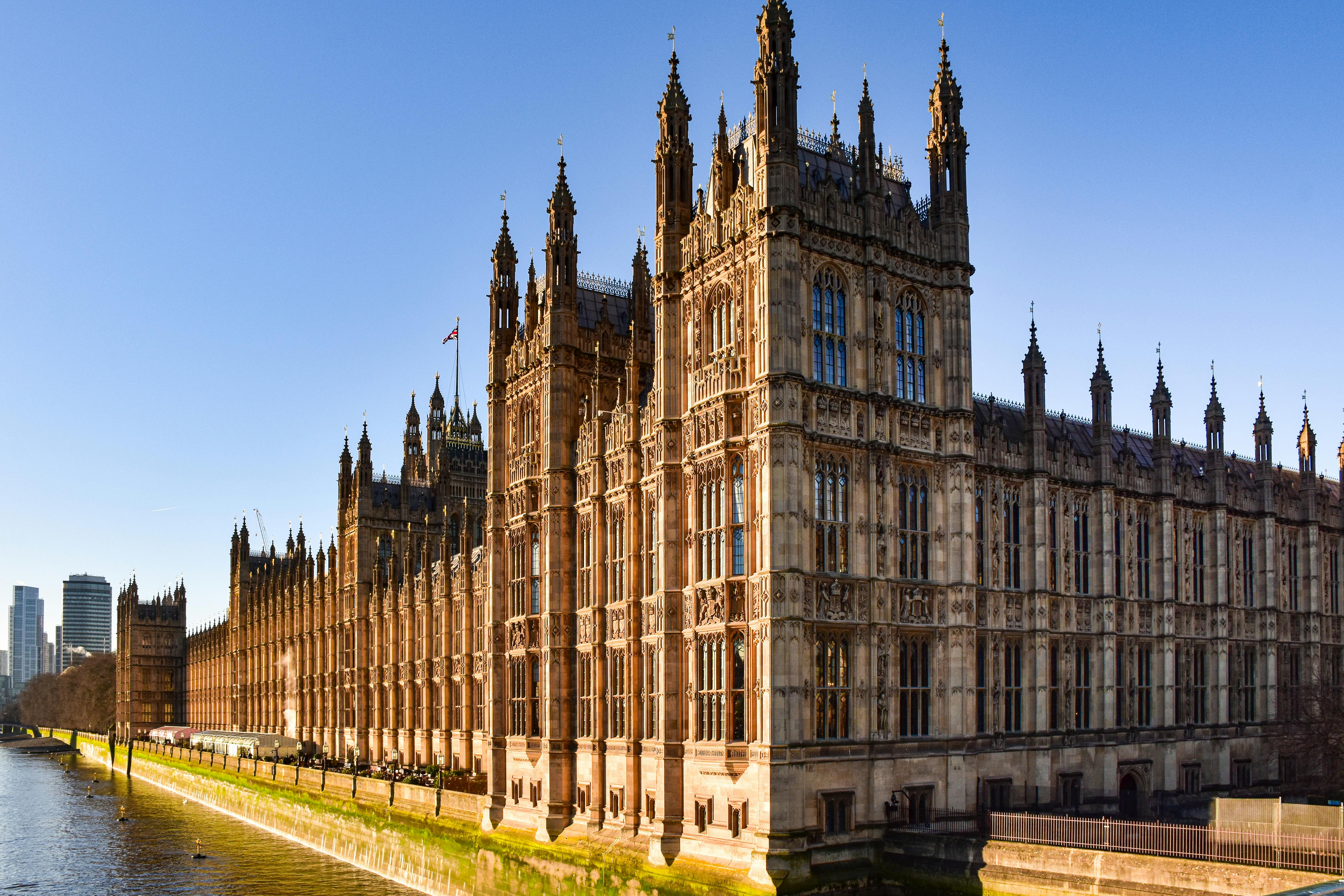 Stunning view of the Houses of Parliament by the Thames River under a clear blue sky.