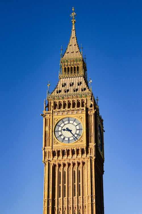 Free The majestic Big Ben tower in London stands tall against a clear blue sky. Stock Photo
