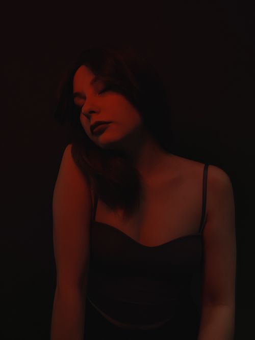 Free Dramatic portrait of a woman under dark red lighting, creating a moody atmosphere. Stock Photo