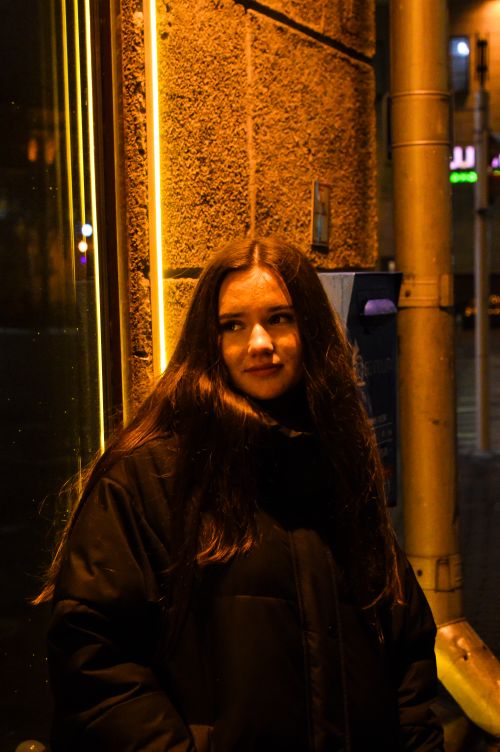 Free A young adult standing under warm street lighting, capturing a moody urban feel at night. Stock Photo