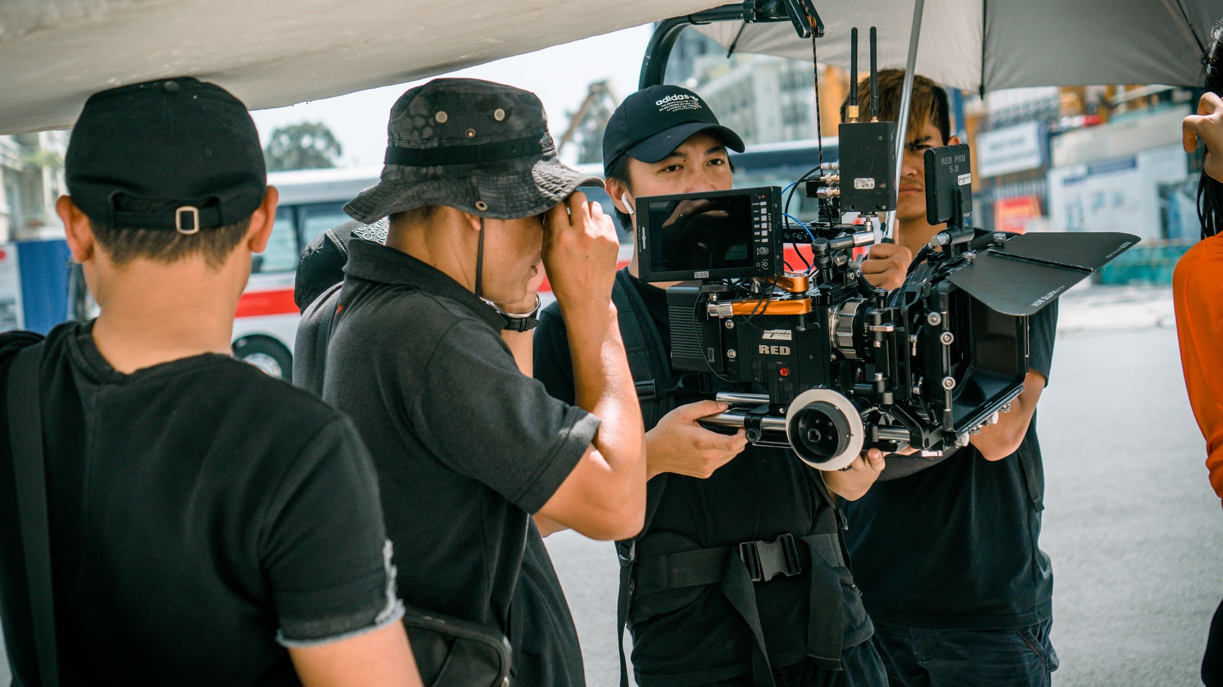 A camera crew on location gathered around a cinema camera during a shoot
