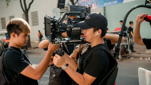 Free Cinematographers setting up professional video gear on an outdoor film set. Stock Photo