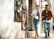 一对时尚情侣戴着墨镜，身着休闲装走在城市街道上