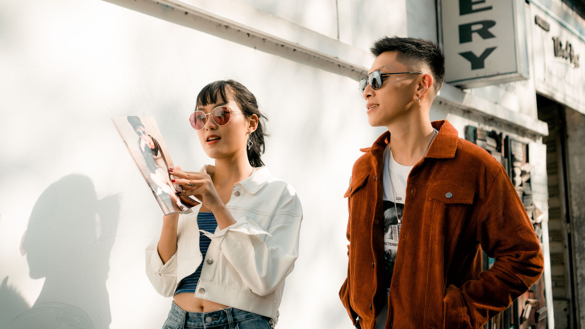Young fashion-forward couple in casual urban attire enjoying a sunny day outdoors.