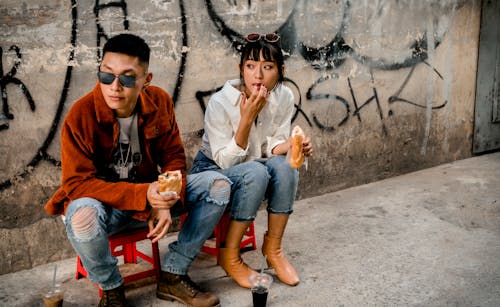 Photo of Man and Woman Eating While Sitting