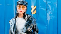 一位戴着太阳镜的时尚年轻女子在蓝色工业背景下摆姿势