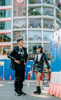 Stylish models posing outdoors in urban setting with modern architecture.