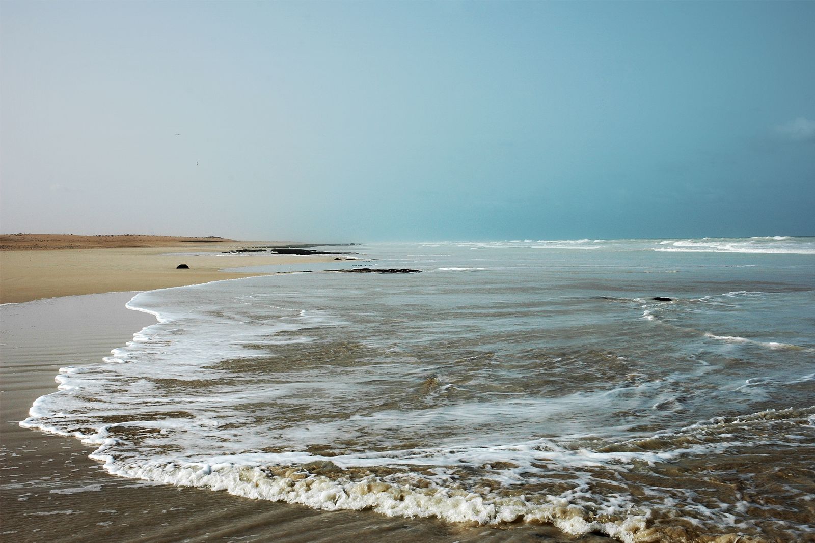 Plage de sable sur la côte marocaine, eaux calmes et horizon infini