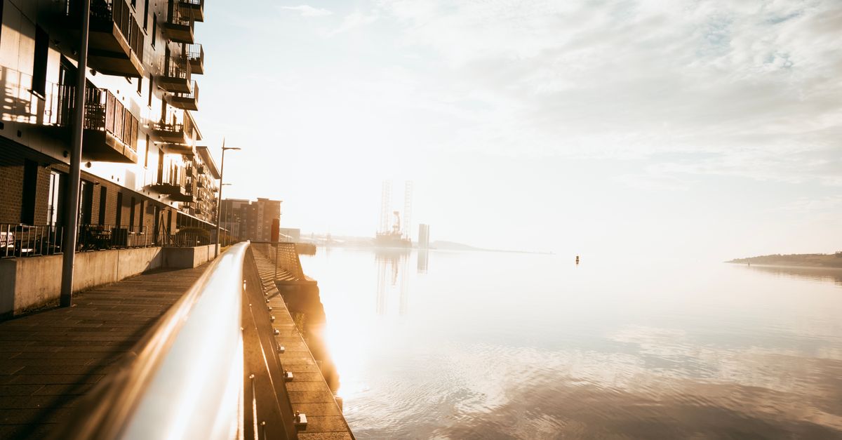 Stunning sunrise over a city waterfront showcasing modern architecture and reflective waters.
