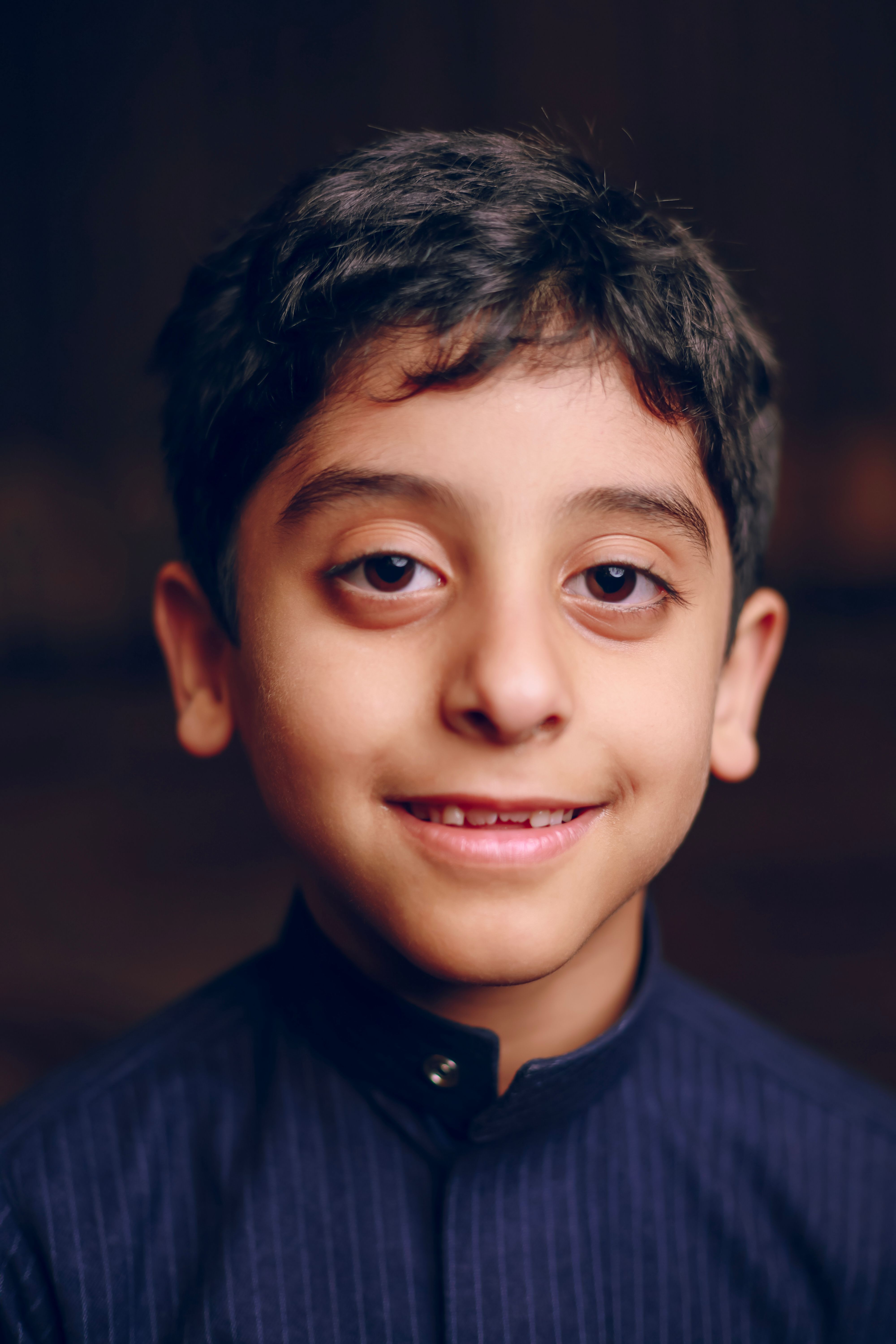 Charming young boy smiling, wearing traditional attire, close-up portrait.