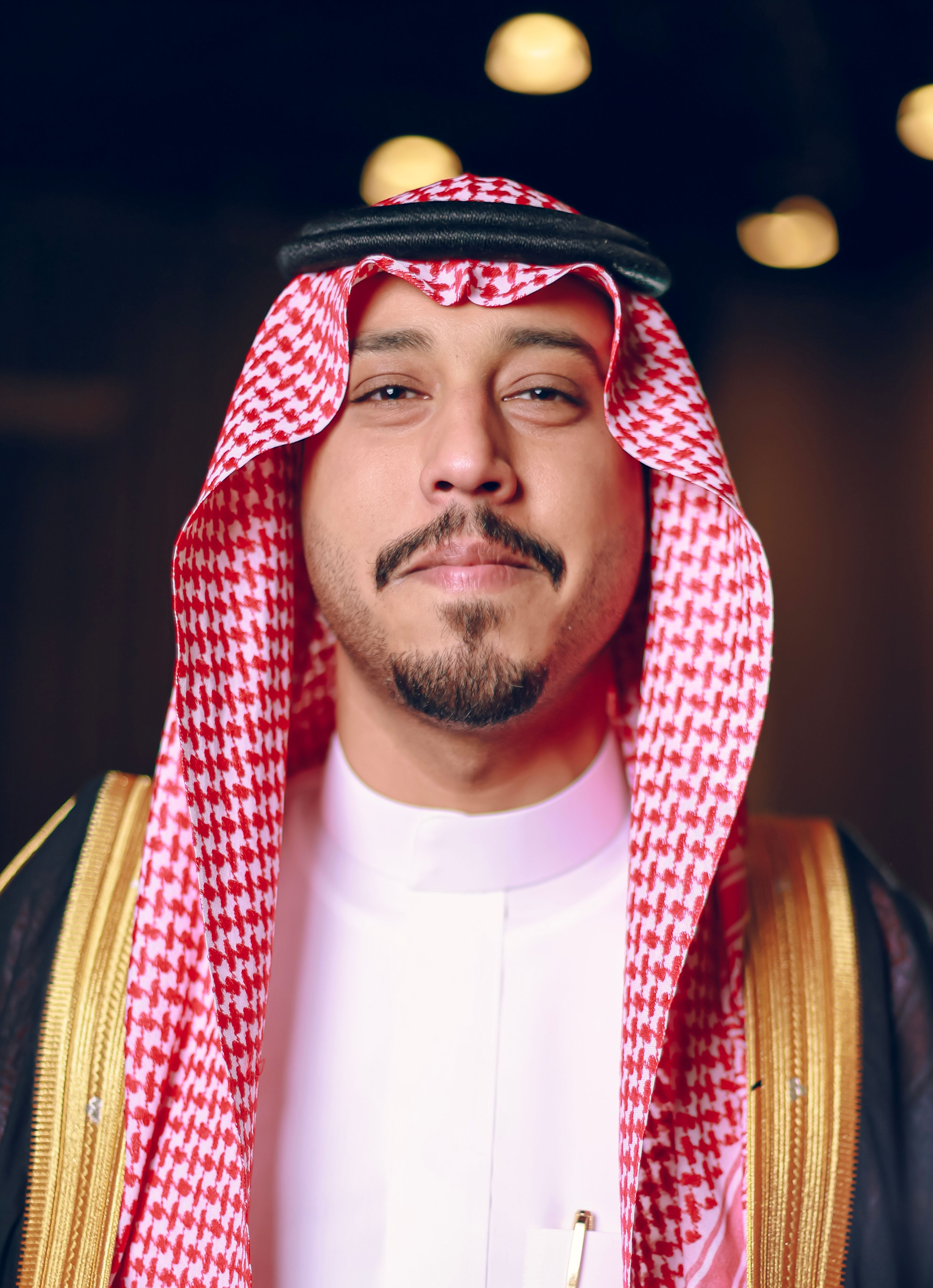 Close-up portrait of a man wearing traditional Middle Eastern attire, smiling confidently.