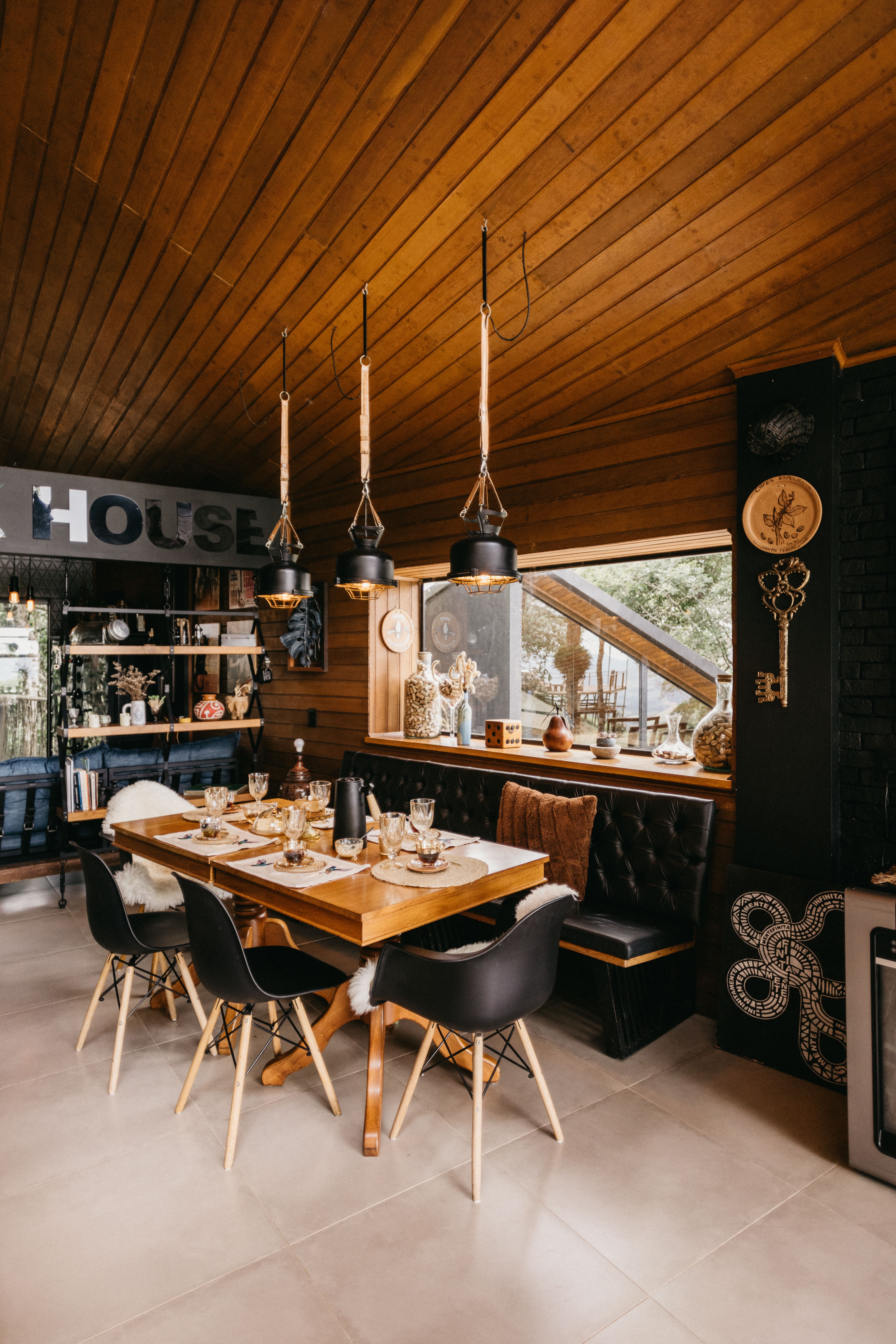 Cozy rustic dining room with wooden ceiling, pendant lights, and a set dining table by a window