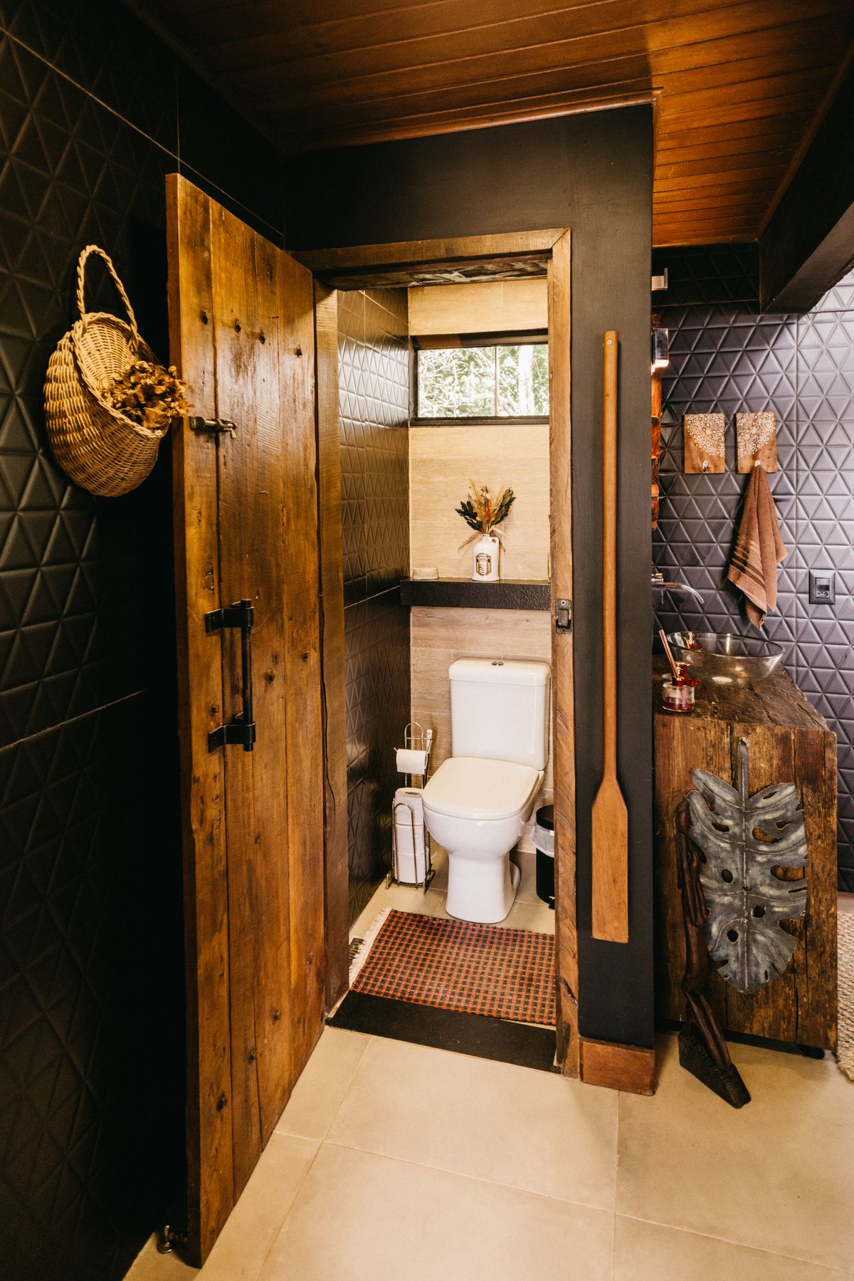 Warm and inviting rustic bathroom featuring wooden elements and black tiles in Espírito Santo, Brazil. Stock Photo.