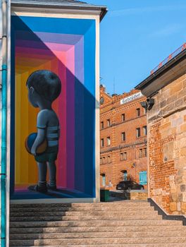 Vibrant mural depicting a child holding a ball on an urban street with historical buildings.
