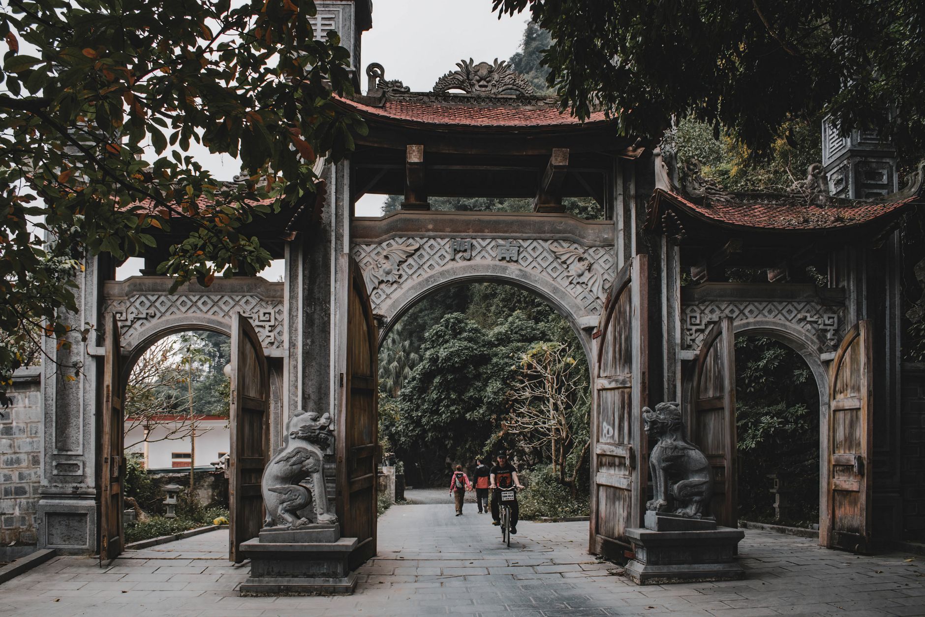 Traditional stone gateway with people and lush greenery in Ninh Bình, Vietnam.