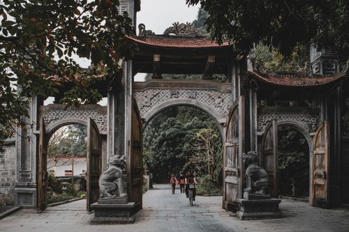 Free Traditional stone gateway with people and lush greenery in Ninh Bình, Vietnam. Stock Photo