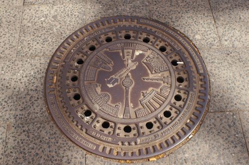 Free Intricate manhole cover in Berlin featuring iconic city landmarks in a detailed design. Stock Photo