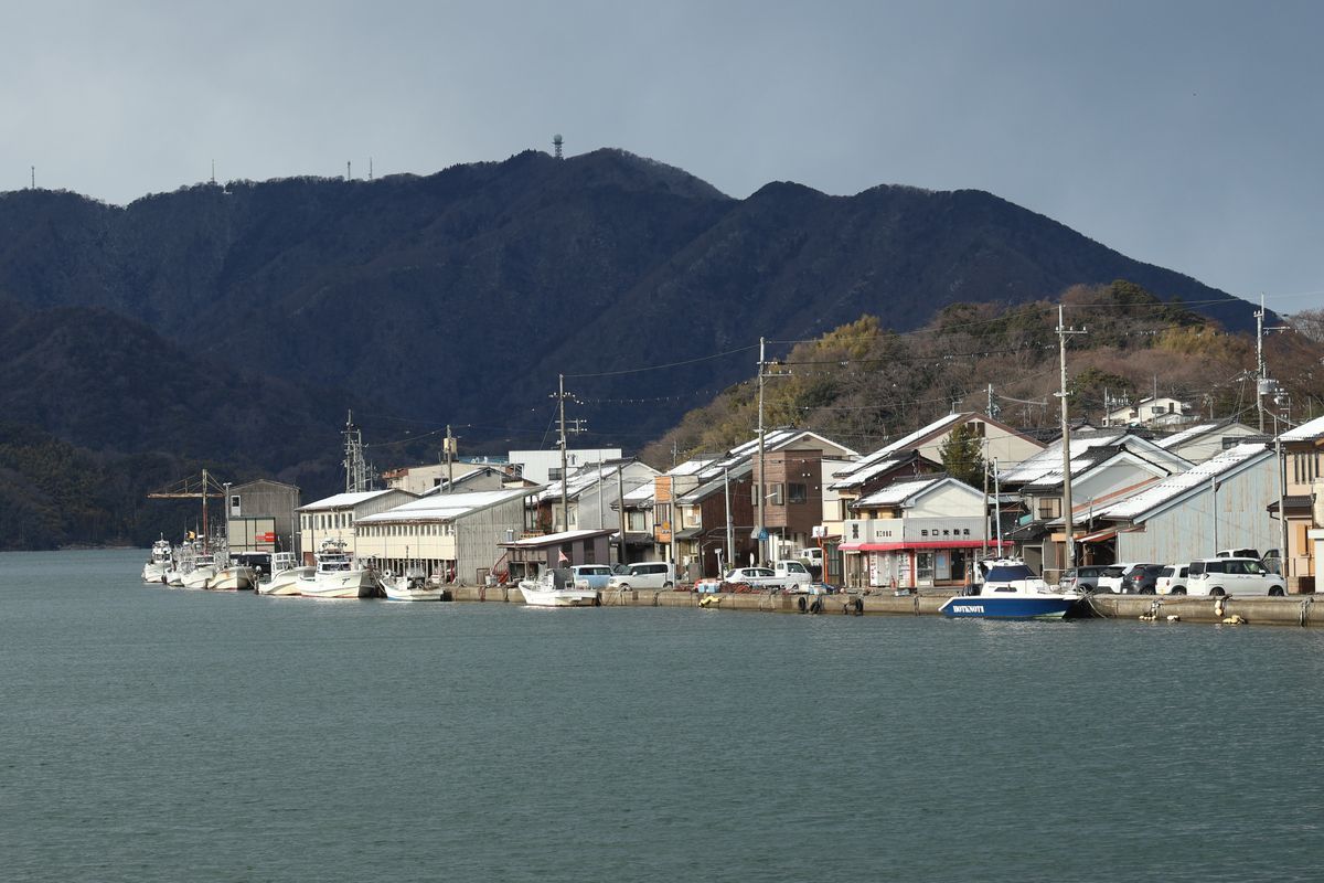 Fishing boats moored at a quiet Japanese port with a mountainous backdrop, typical of working harbors on the Seto Inland Sea like Tomonoura