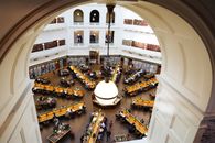 High-angle shot of a crowded dome library room with study tables and shelves.
