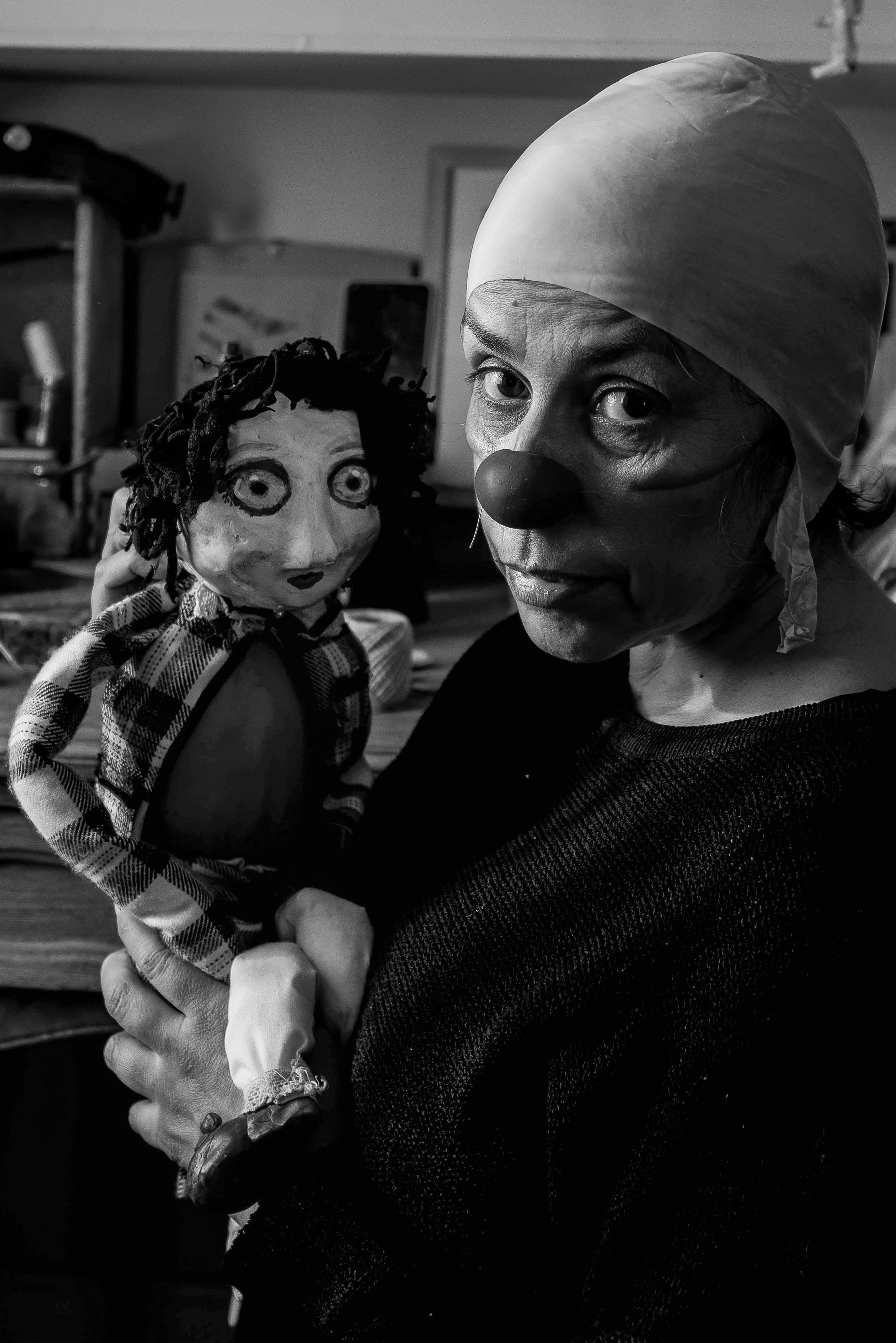 De franc Una foto malhumorada en blanc i negre d'un pallasso sostenint un titella en un entorn artístic. Foto d'estoc