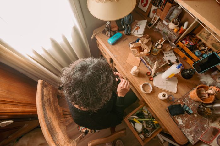 Overhead view of an artist working in a cluttered studio, photo by Natalia Olivera on Pexels