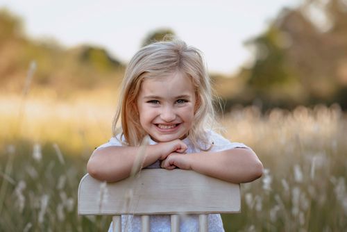 Free A joyful child with blonde hair smiling in a sunlit meadow, symbolizing happiness and freedom. Stock Photo
