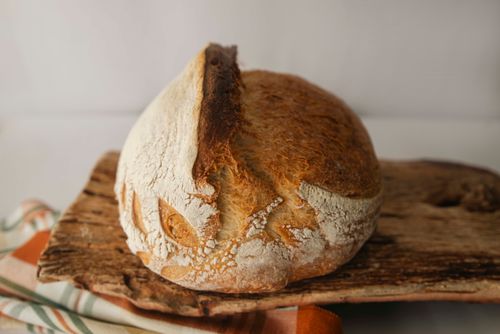 Free Freshly baked artisan sourdough loaf on a rustic wooden board, perfect for bakery themes. Stock Photo