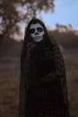 黄昏时分，一位化着骷髅妆、戴着深色面纱的神秘女子在户外展现了万圣节精神