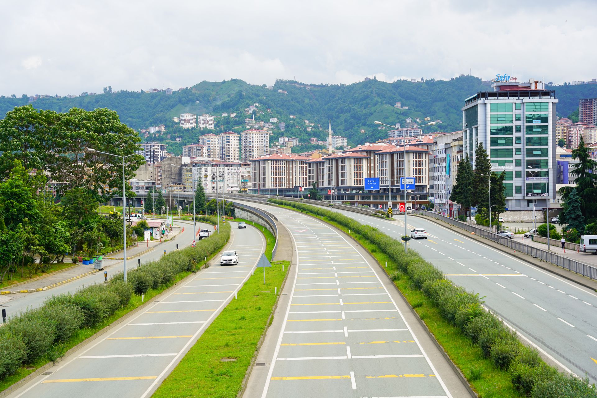 Scenic view of Rize city, Türkiye, with modern buildings, street, and lush green hills.