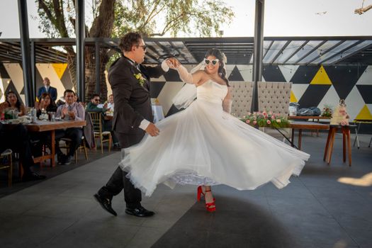 Happy newlywed couple dancing with joy outdoors in a stylish venue.
