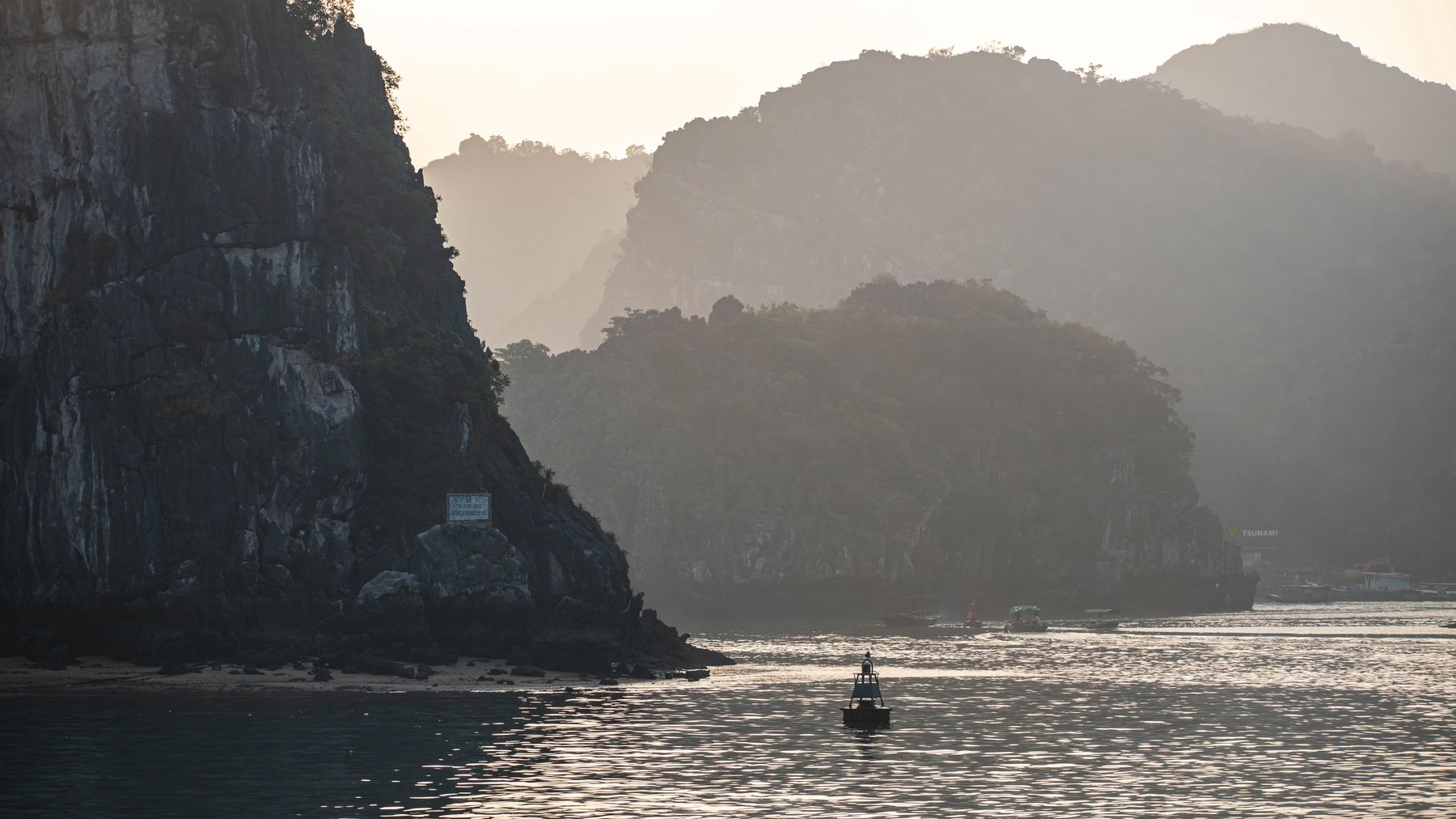 Peaceful view of Ha Long Bay with limestone cliffs in the evening light.